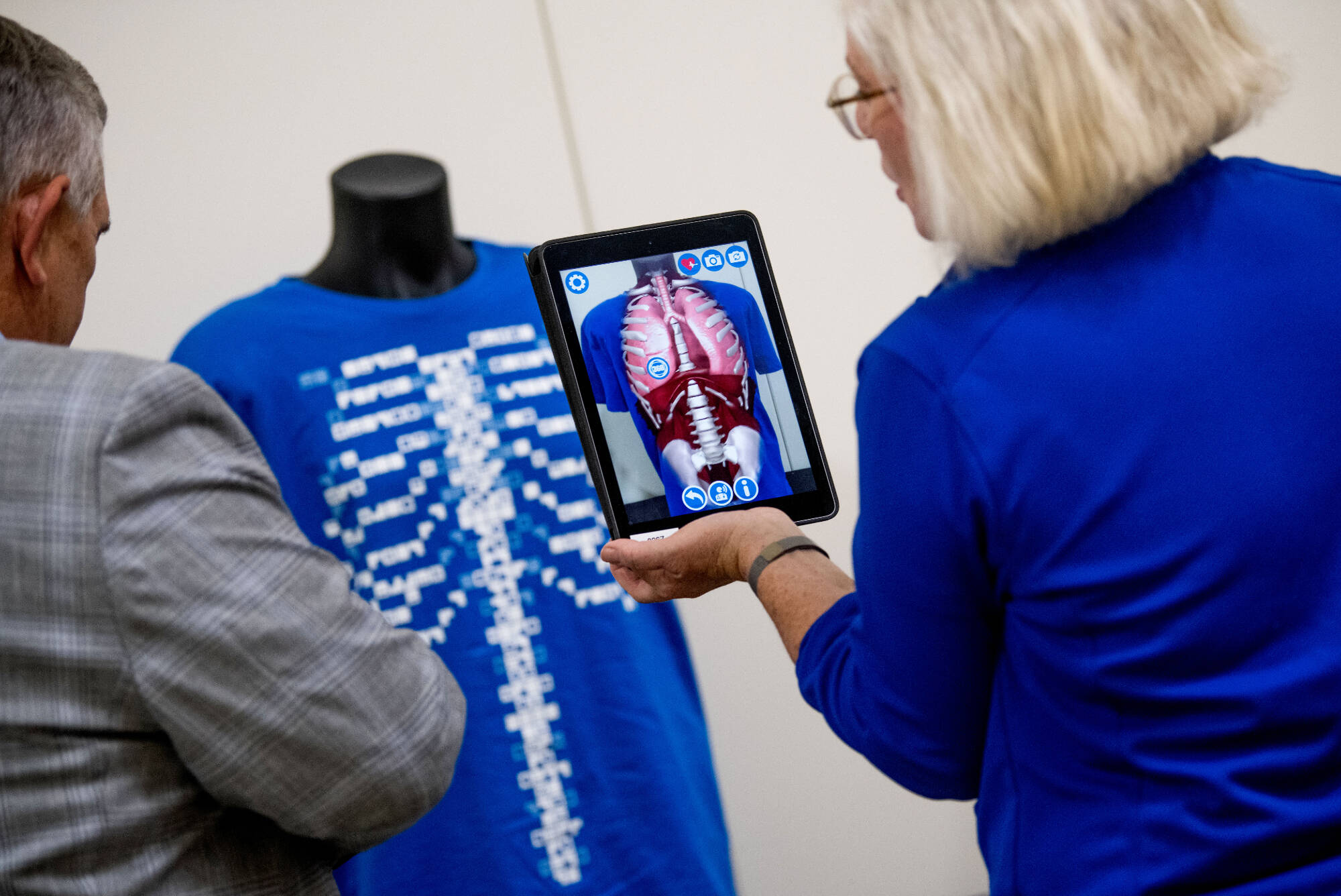 A person holding a tablet pointed towards a shirt with a skeletal design.